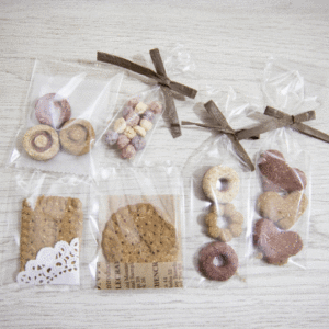 ハートの形のクッキーや、小さなドーナツ、ビスケットが、茶色い上品なリボンのついたふくろにはいっている写真（人がまちがってたべてしまいそうなかんじ）