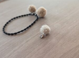 ３色のことなるベージュ系の色の毛でつくった３つの小さな毛の球でつくったヘアーアクセサリ